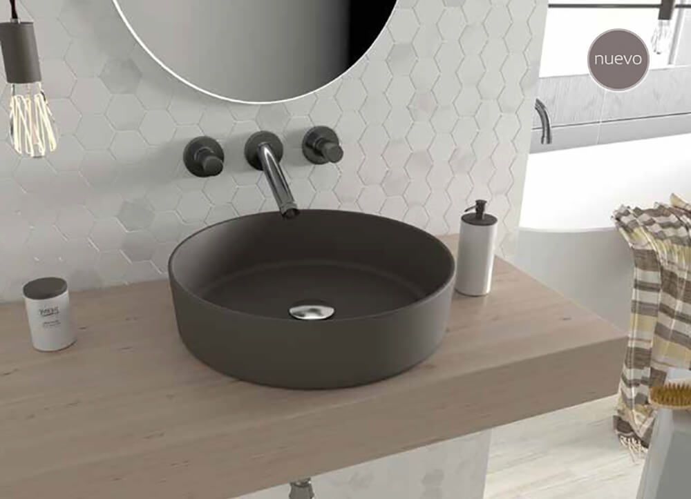 Lavabo de baño con pila oscura, grifo cromado y dispensador de jabón sobre encimera de madera.