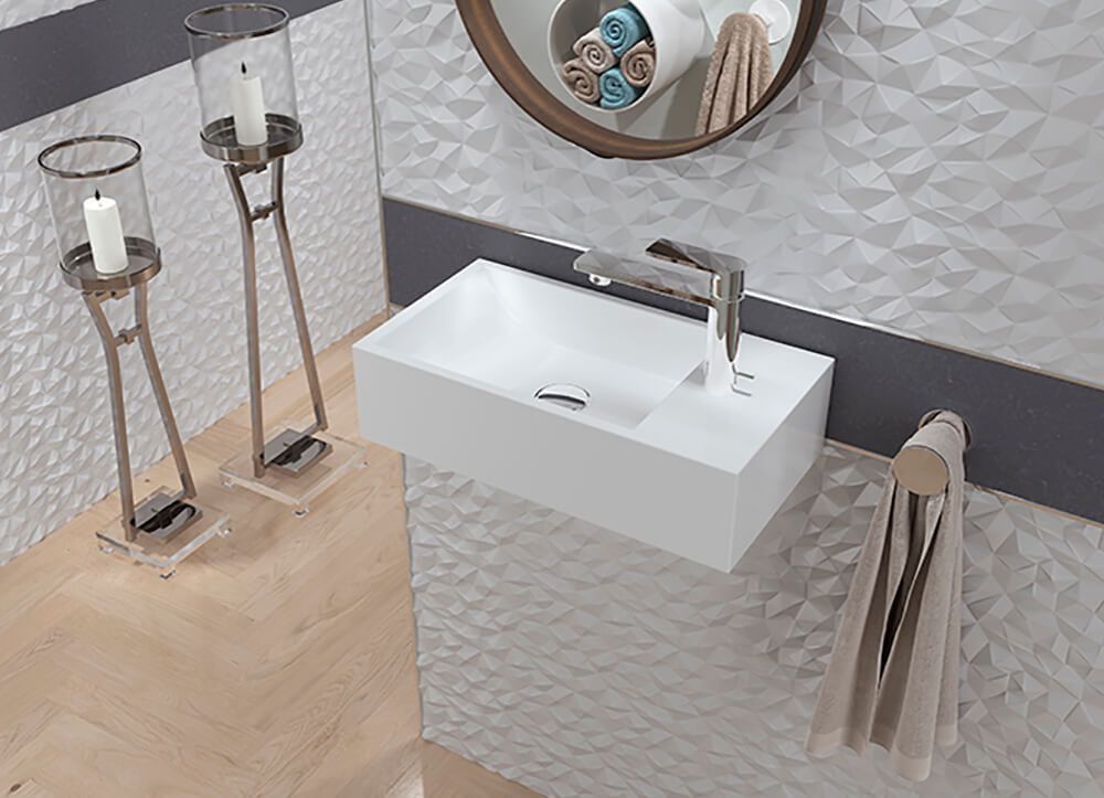 Lavabo de baño moderno blanco sobre una pared texturizada, con espejo, toallas y candelabros decorativos.