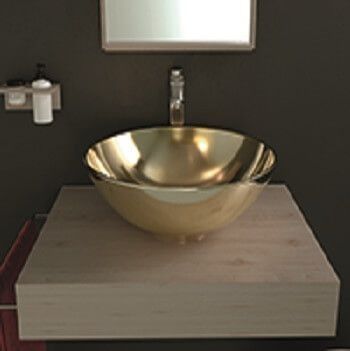 Lavabo dorado sobre mueble flotante de madera clara. Grifo cromado, espejo y pared oscura.