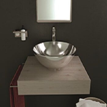 Lavabo de acero inoxidable sobre un tocador flotante de madera en un baño oscuro con espejo.