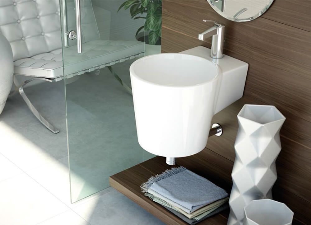 Lavabo de baño blanco con grifo y toallas en un estante; pared de madera y una silla visibles.