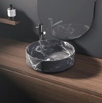 Lavabo de baño redondo de mármol negro sobre encimera de madera con espejo.