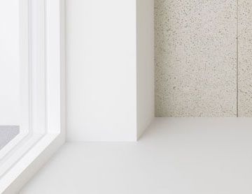 Rincón interior blanco con ventana y pared texturizada.