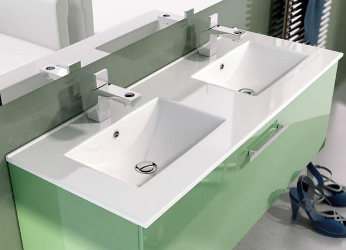 Tocador de baño verde con dos lavabos blancos, grifos cromados y un espejo.