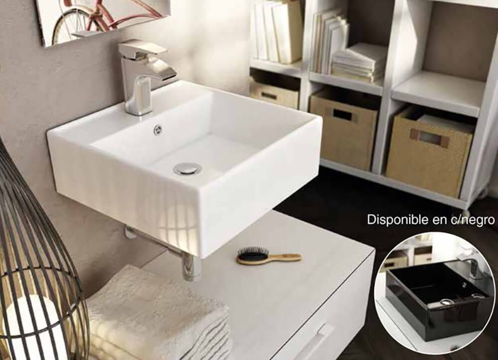 Lavabo blanco cuadrado de pared con grifo cromado. Mueble blanco con cajones debajo. Estantería con cajas de almacenaje al fondo.