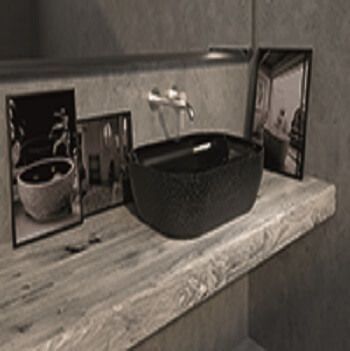 Lavabo de baño negro sobre estante de madera con fotografías enmarcadas y grifo cromado.