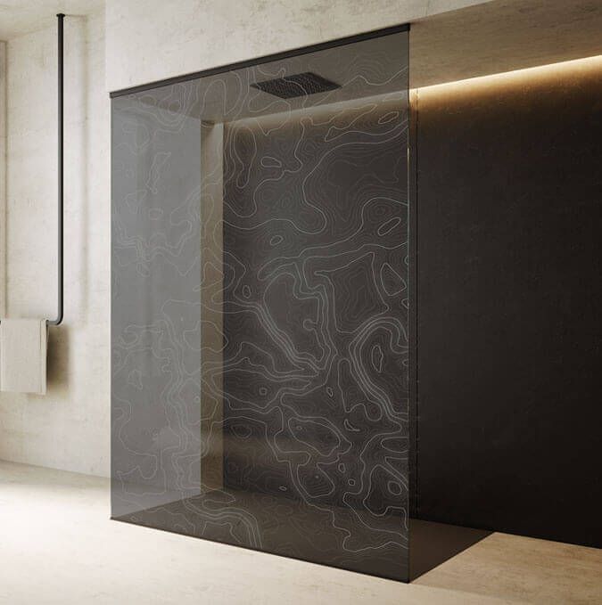 Ducha moderna con panel de vidrio estampado, paredes negras y cabezal de ducha superior.