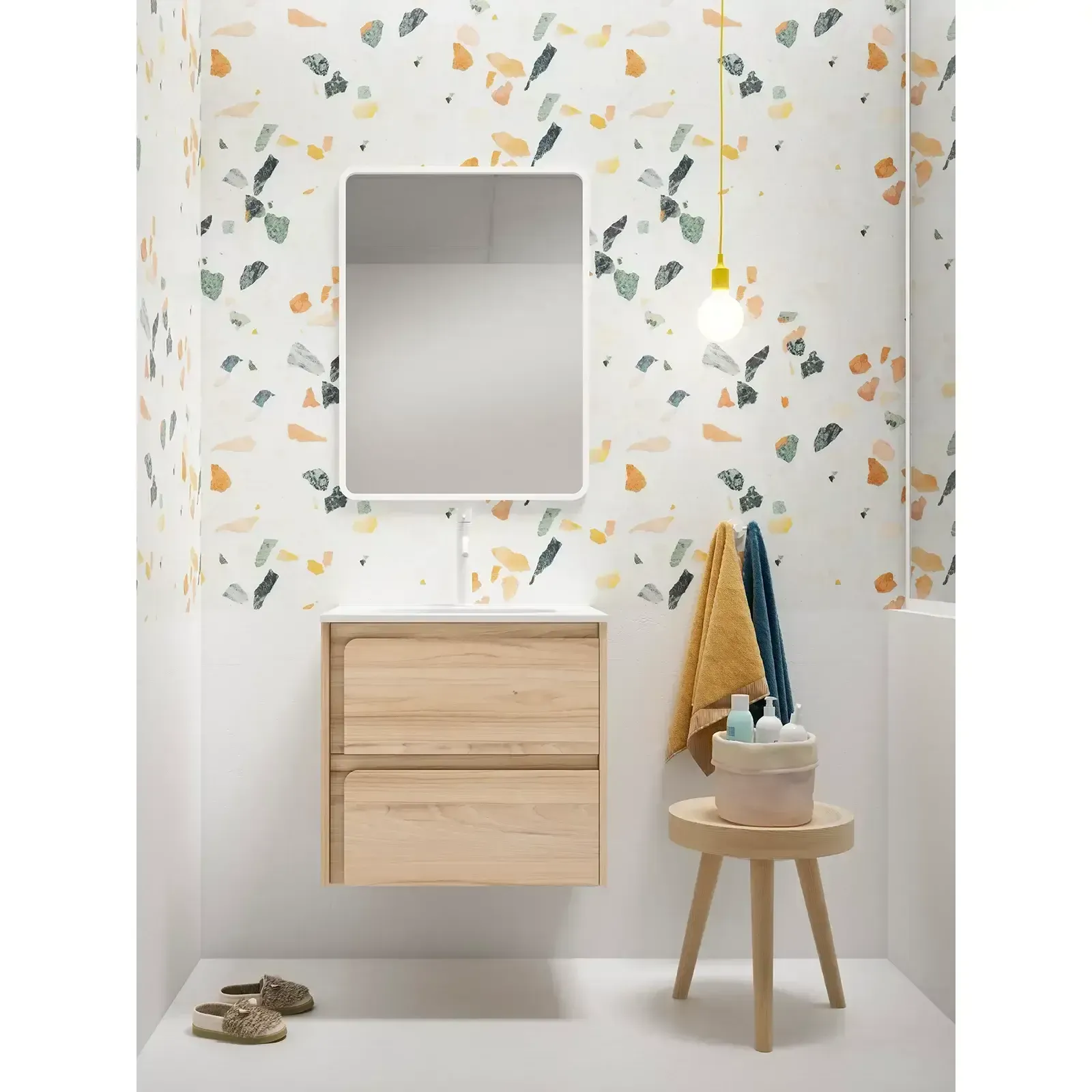 Baño con tocador de madera, papel pintado estampado, espejo, taburete, toallas y lámpara colgante.