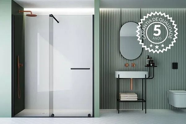 Baño moderno con ducha de cristal, accesorios negros y pared verde. Insignia de garantía de calidad de 5 años visible.
