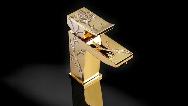 Grifo de baño en color dorado con grabados florales sobre fondo negro.