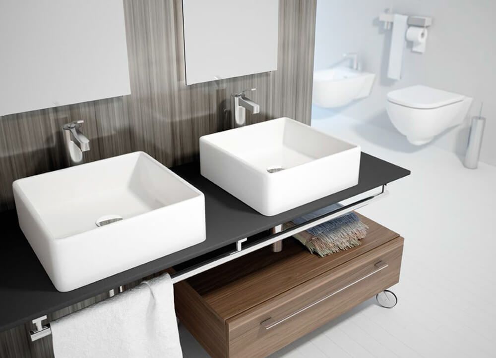 Baño moderno con dos lavabos cuadrados blancos, mueble de madera e inodoro suspendido.