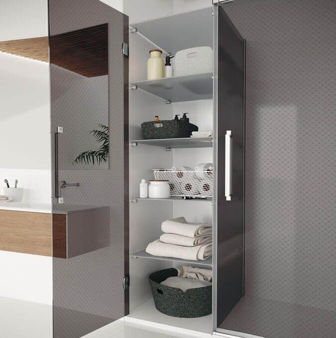 Mueble de baño alto y oscuro abierto, dejando al descubierto estantes con artículos de tocador y toallas.