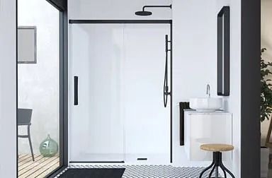 Baño moderno con ducha con marco negro, tocador flotante de madera, espejo circular, paredes grises y un inodoro blanco.