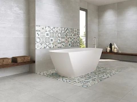 Baño moderno con bañera blanca, azulejos decorativos estampados y paredes grises.