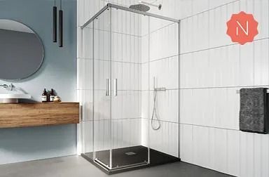 Baño moderno con mampara de ducha de cristal, base de ducha de color negro, paredes de azulejos blancos y espejo redondo.