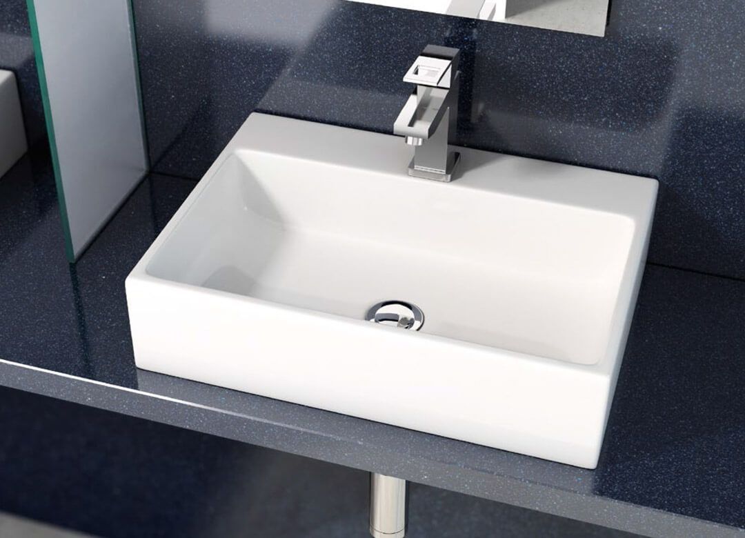 Lavabo de baño rectangular blanco con grifo cromado sobre encimera oscura.