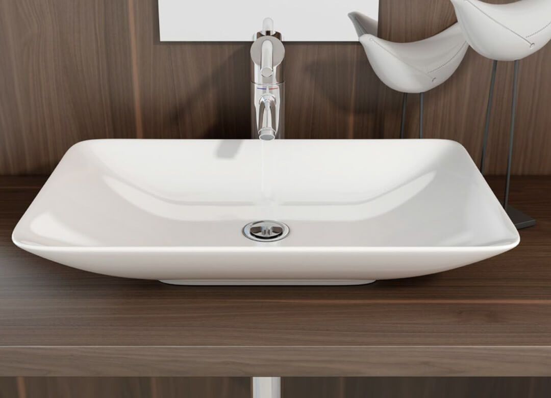 Lavabo de baño rectangular blanco con grifo cromado sobre encimera de madera marrón.