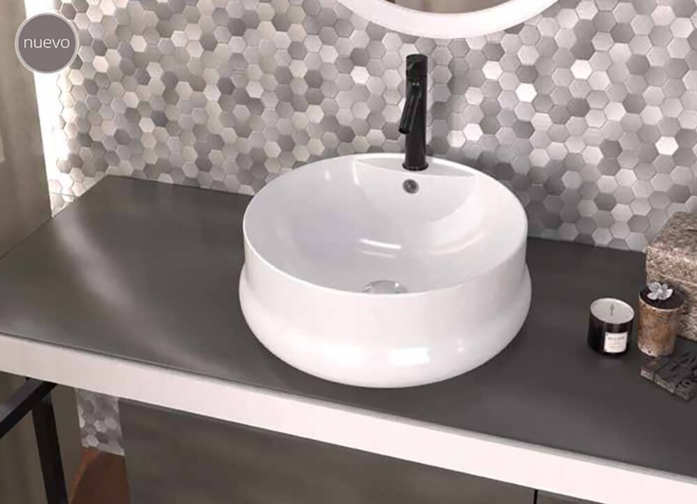 Lavabo blanco sobre encimera gris con grifo negro y salpicadero de azulejos con diseño de panal.
