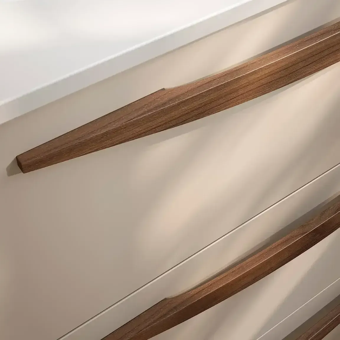 Primer plano de una cómoda blanca y beige con tres tiradores de madera marrones.