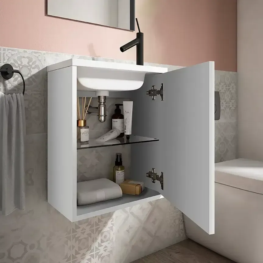 Mueble de baño de pared de color blanco con puerta abierta, que contiene un lavabo y artículos de aseo.