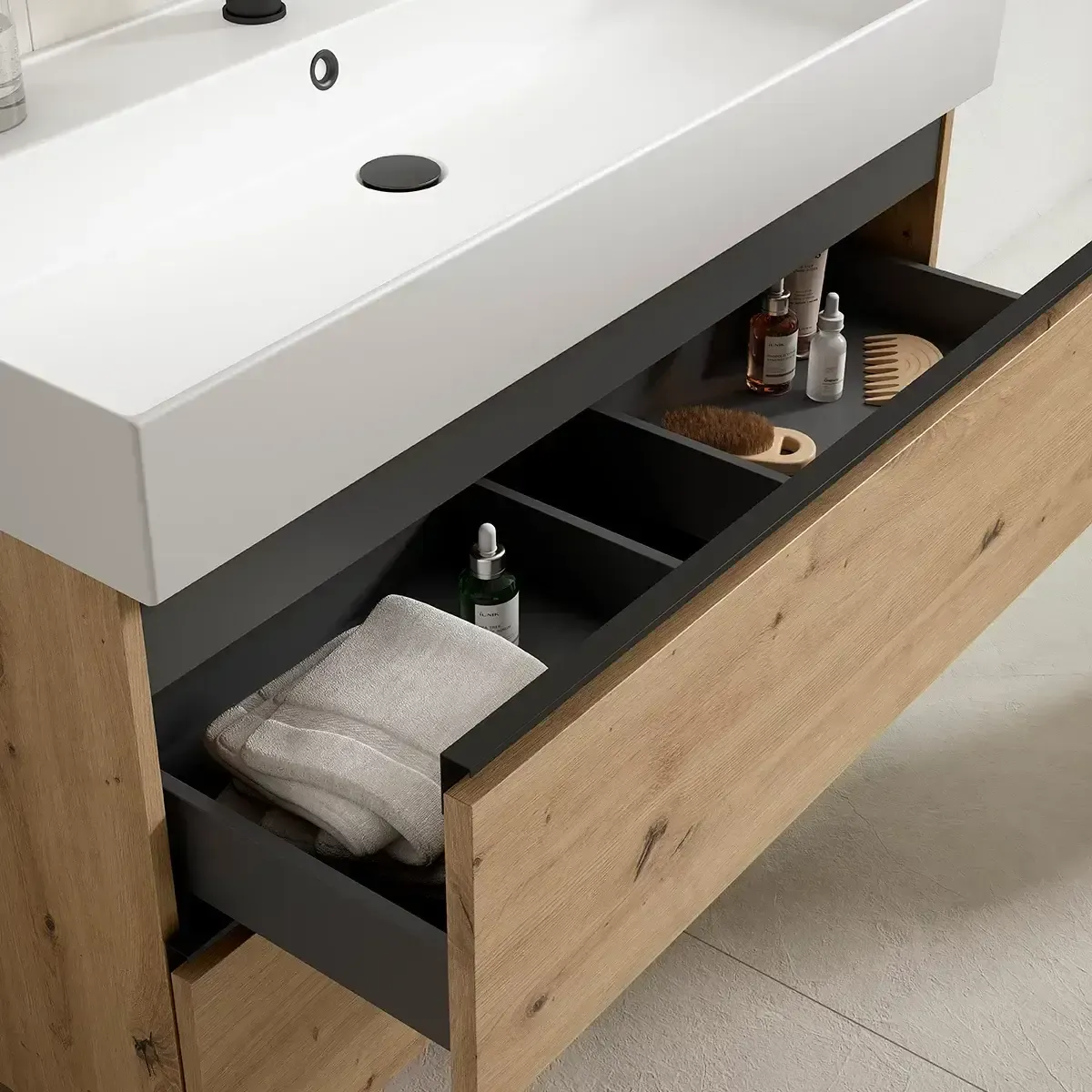 Mueble de baño con cajón abierto; toalla, artículos de aseo y peine. Mueble de madera y lavabo blanco.