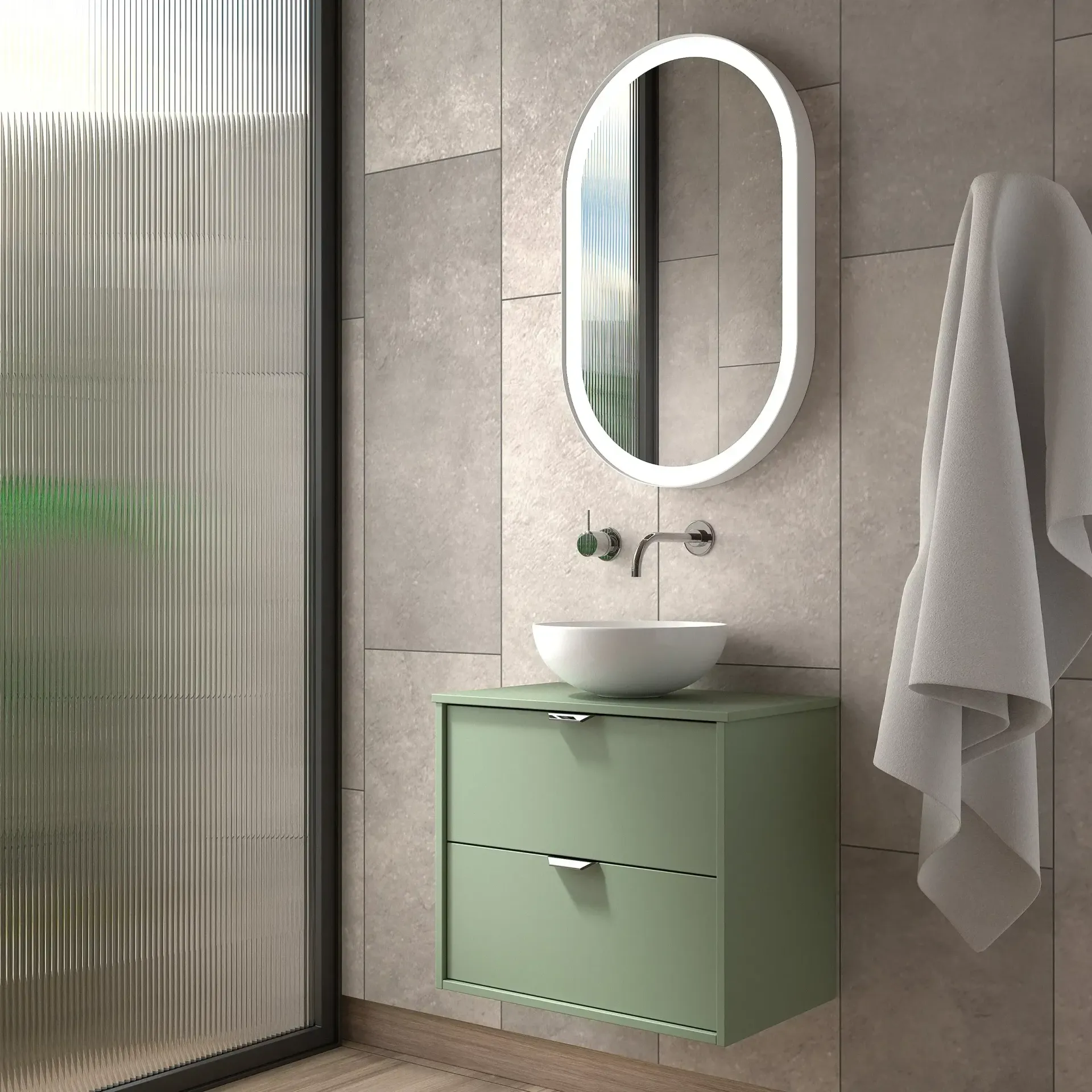 Tocador verde con lavabo blanco, espejo ovalado y toalla colgada en una pared de azulejos.