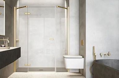 Baño moderno con ducha de cristal, inodoro flotante, accesorios dorados y lavabo de color oscuro.