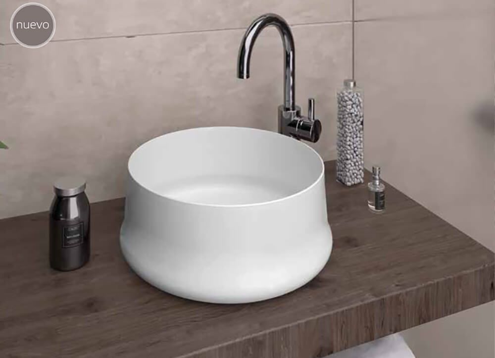 Lavabo de lavabo blanco sobre encimera de madera con grifería cromada.