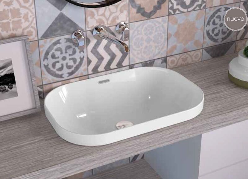 Lavabo de baño ovalado blanco sobre encimera de madera, con protector contra salpicaduras estampado y grifo cromado.