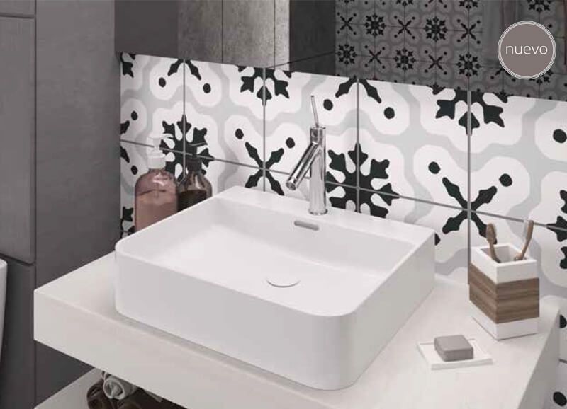 Lavabo rectangular blanco sobre un estante blanco en un baño con azulejos estampados en blanco y negro.