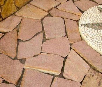 Pasarela de losas de tono rosa con borde de mosaico, vista de cerca.