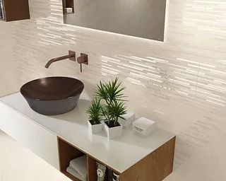 Baño moderno con lavabo de sobremesa, grifo de cobre y salpicadero de azulejos de color crema.