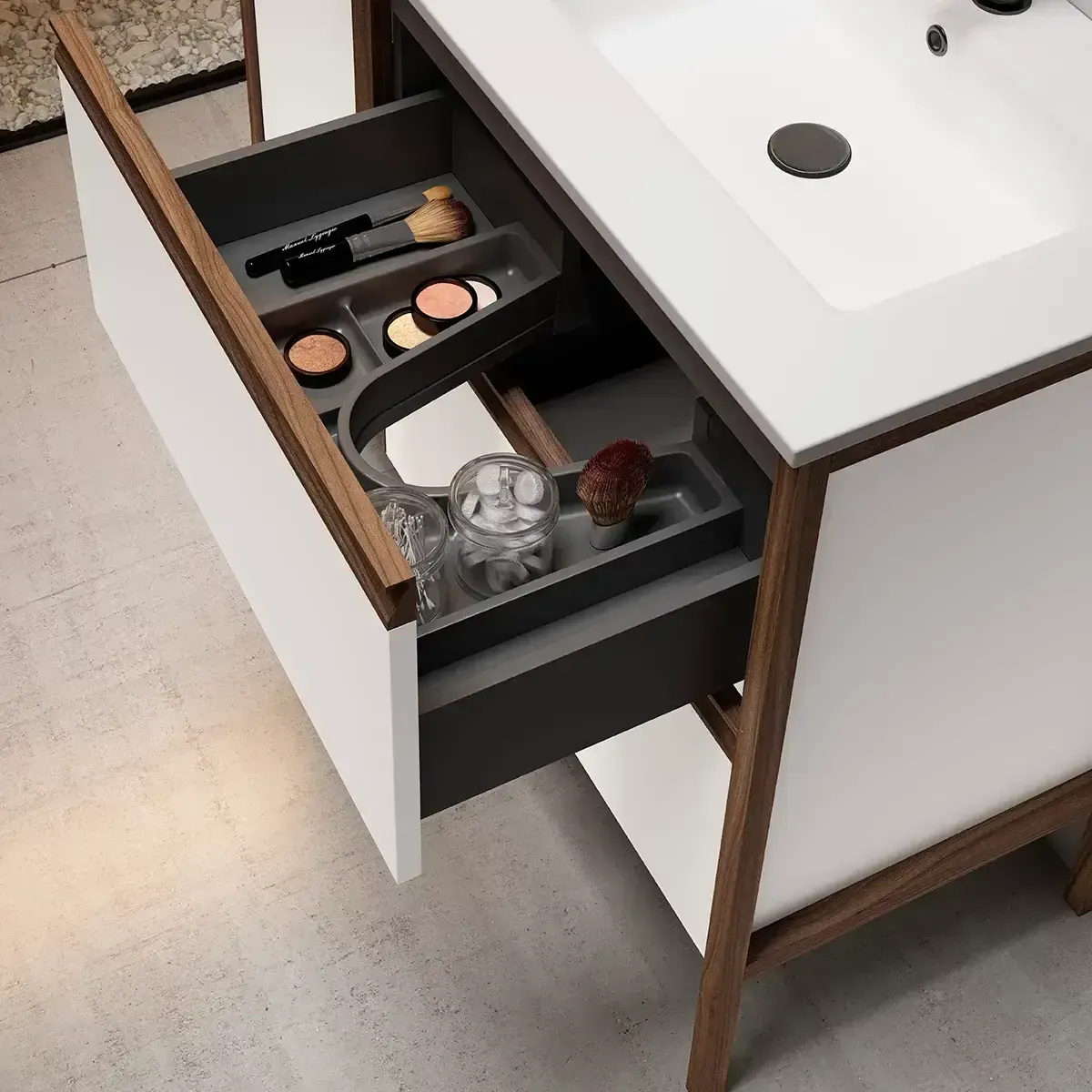 Tocador con cajón abierto que muestra maquillaje y accesorios; mueble blanco, moldura de madera.