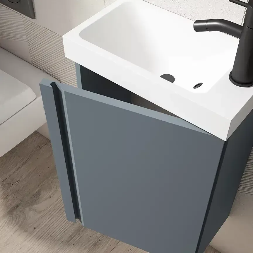 Pequeño mueble de baño de color azul con puerta abierta y grifería de color negro.