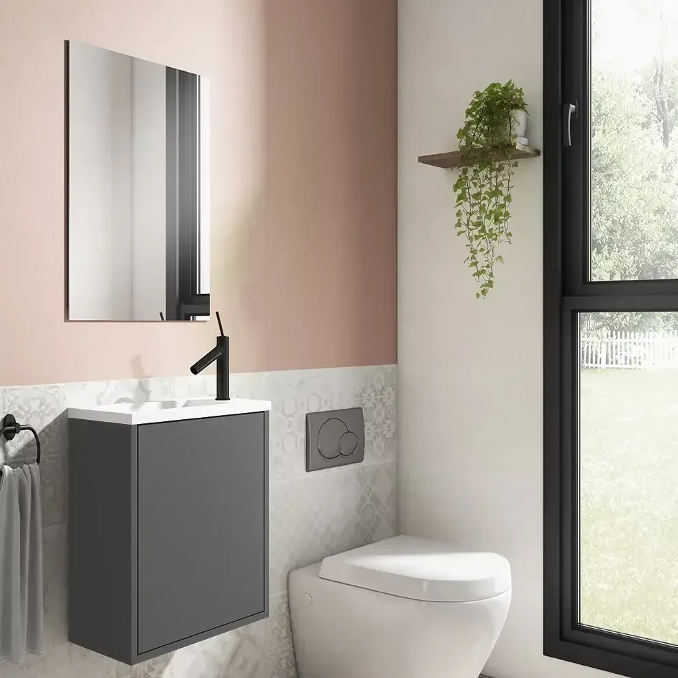 Baño moderno con tocador gris, espejo, inodoro y ventana. Paredes rosas y blancas.