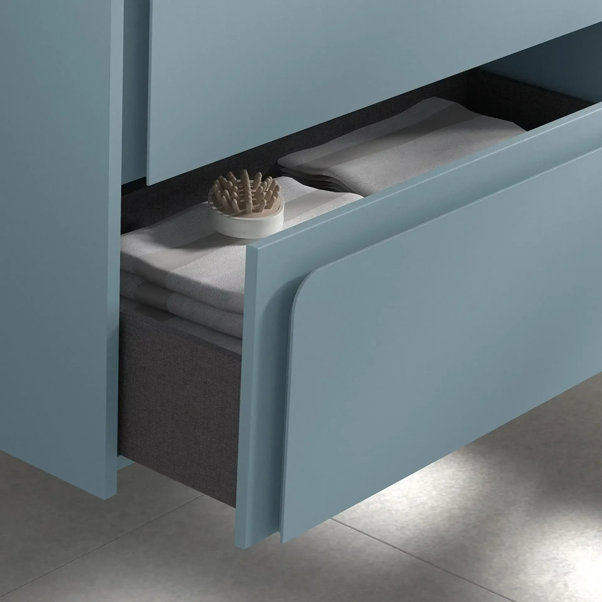 Cajón de mueble de baño de color azul con toallas y un cepillo.