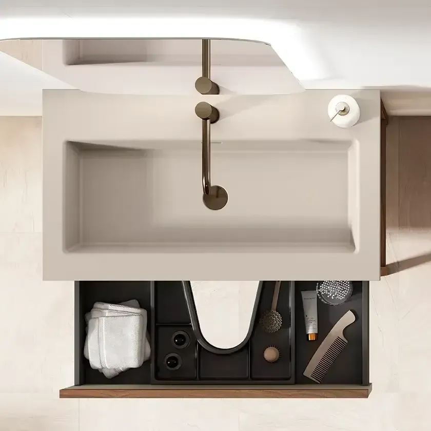 Lavabo rectangular beige con cajón abierto; artículos de aseo y toallas. Grifo de techo.