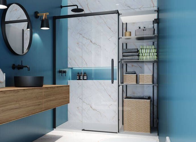 Baño con paredes azules, accesorios negros, tocador de madera, ducha de mármol y estantería.