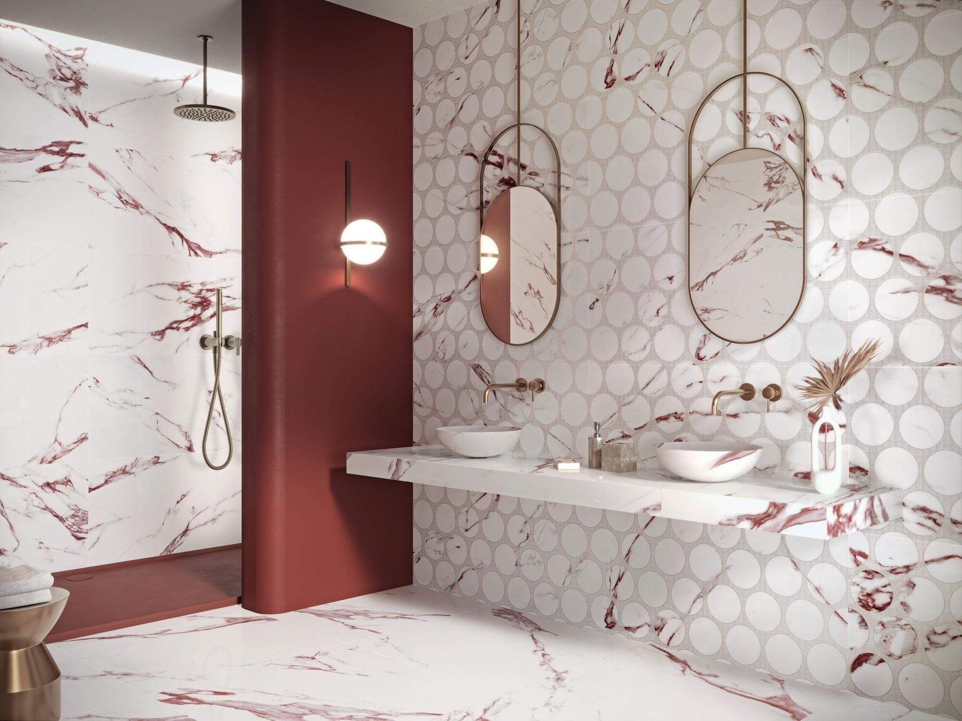 Baño con azulejos con diseño de mármol rojo, pared con acento rojo, accesorios dorados y espejos ovalados.