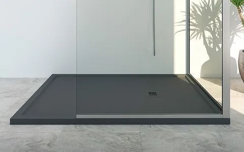 Base de ducha de color gris oscuro con mampara de cristal sobre suelo de baldosas de color claro.