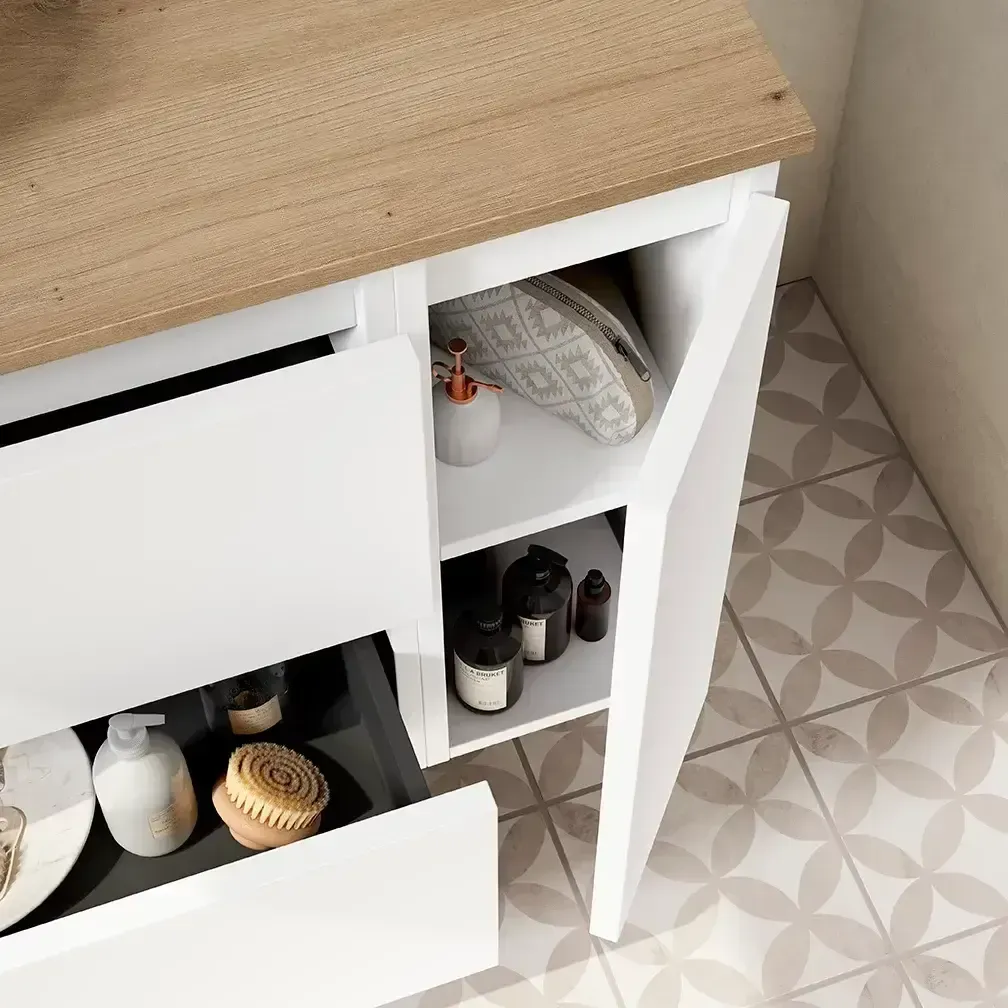 Mueble de baño blanco con cajón abierto y puerta lateral. Encimera de madera y estantes con artículos de tocador.