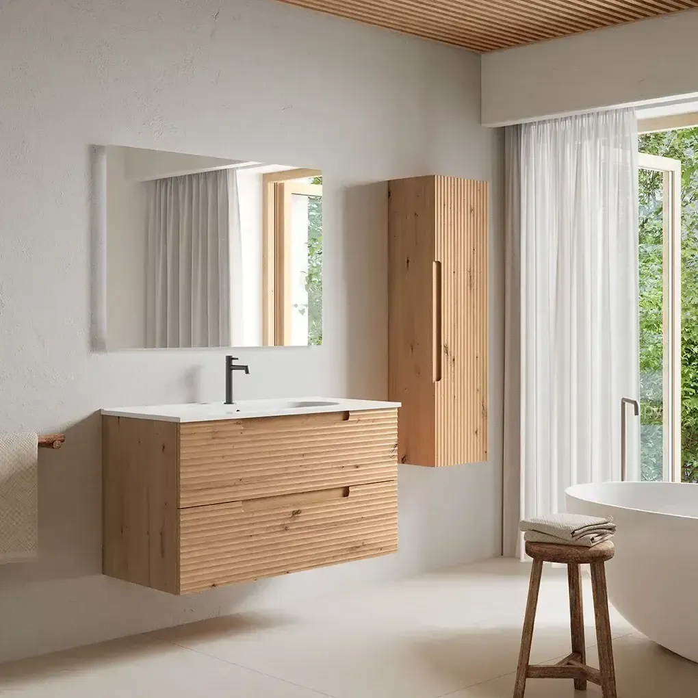 Baño con tocador de madera, mueble alto, espejo y bañera independiente cerca de una ventana con cortinas blancas.