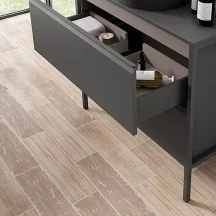 Mueble de baño gris con cajón abierto, suelo de madera.