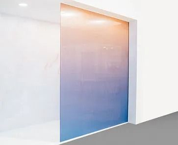 Interior de paredes blancas con panel de vidrio; gradiente de colores que transitan del naranja al azul.