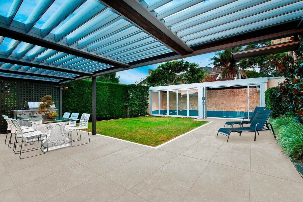 Patio con pérgola, zona de estar, césped y piscina cerrada.