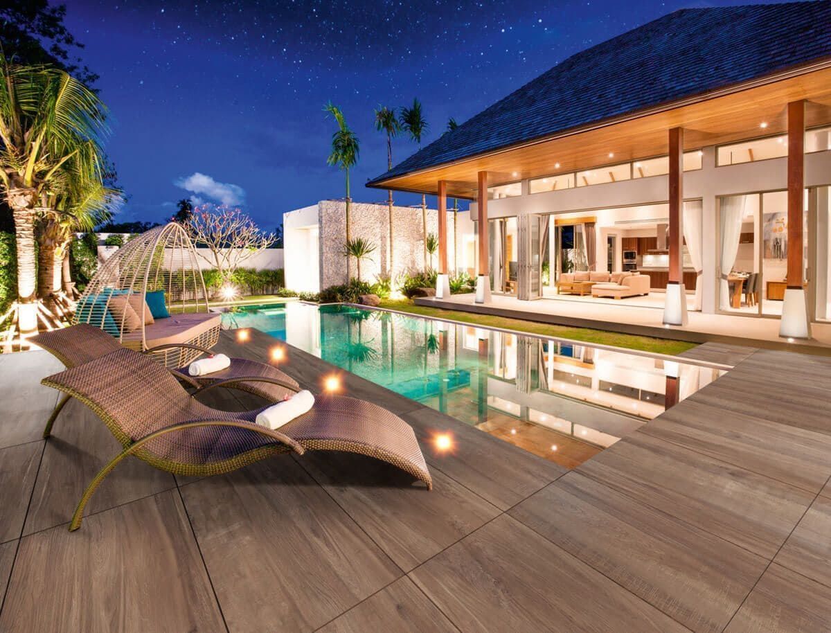 Villa de lujo de noche con piscina, tumbonas y cielo estrellado.