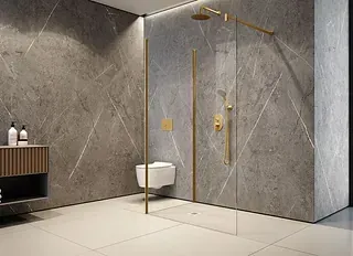Baño moderno con paredes de mármol gris, accesorios dorados y ducha de cristal.