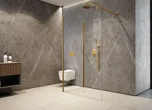 Baño moderno con paredes de mármol gris, accesorios dorados y ducha de cristal.