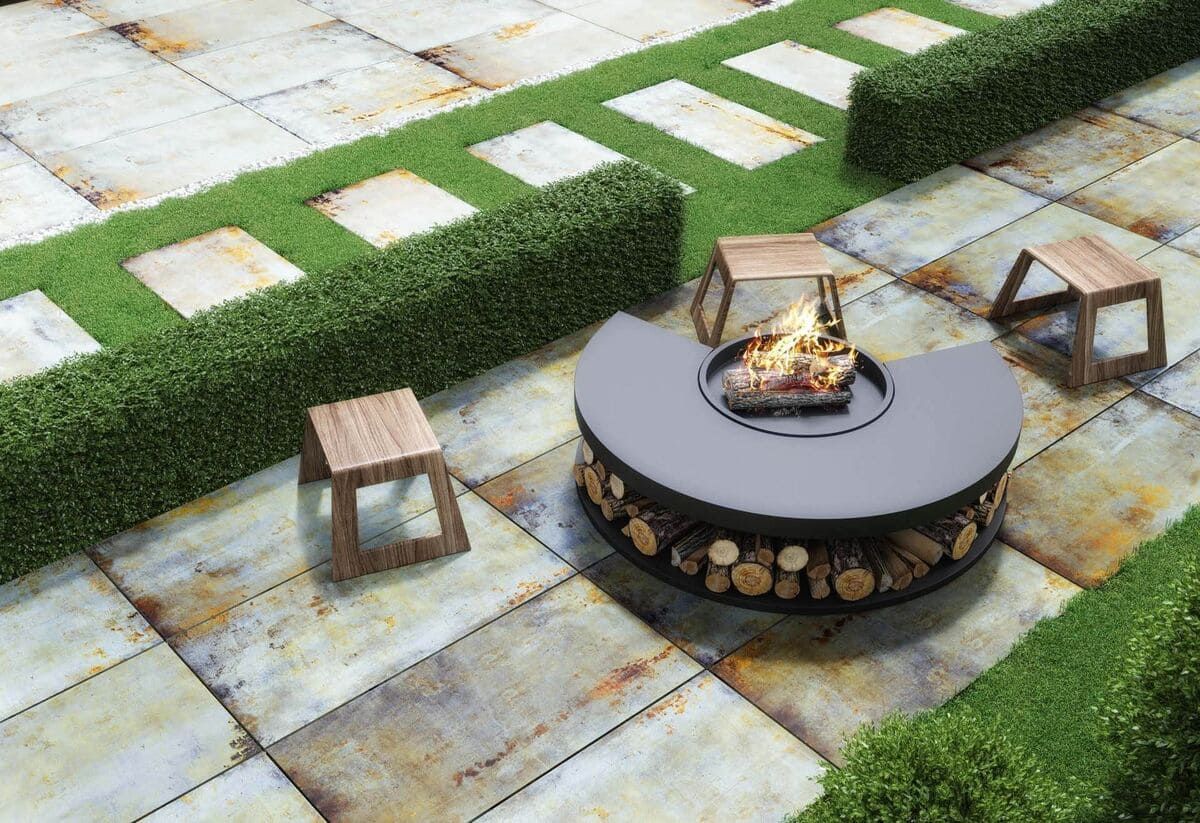 Área de fogata con taburetes de madera y seto.