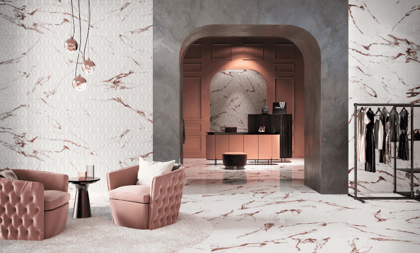 Un espacio comercial de lujo con pisos de mármol rosa, detalles a juego y sillones de terciopelo.